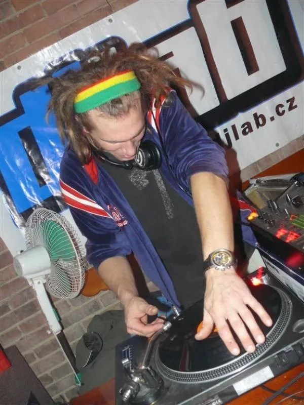 Young DJ Kita with dreadlocks and a rasta headband scratching a record