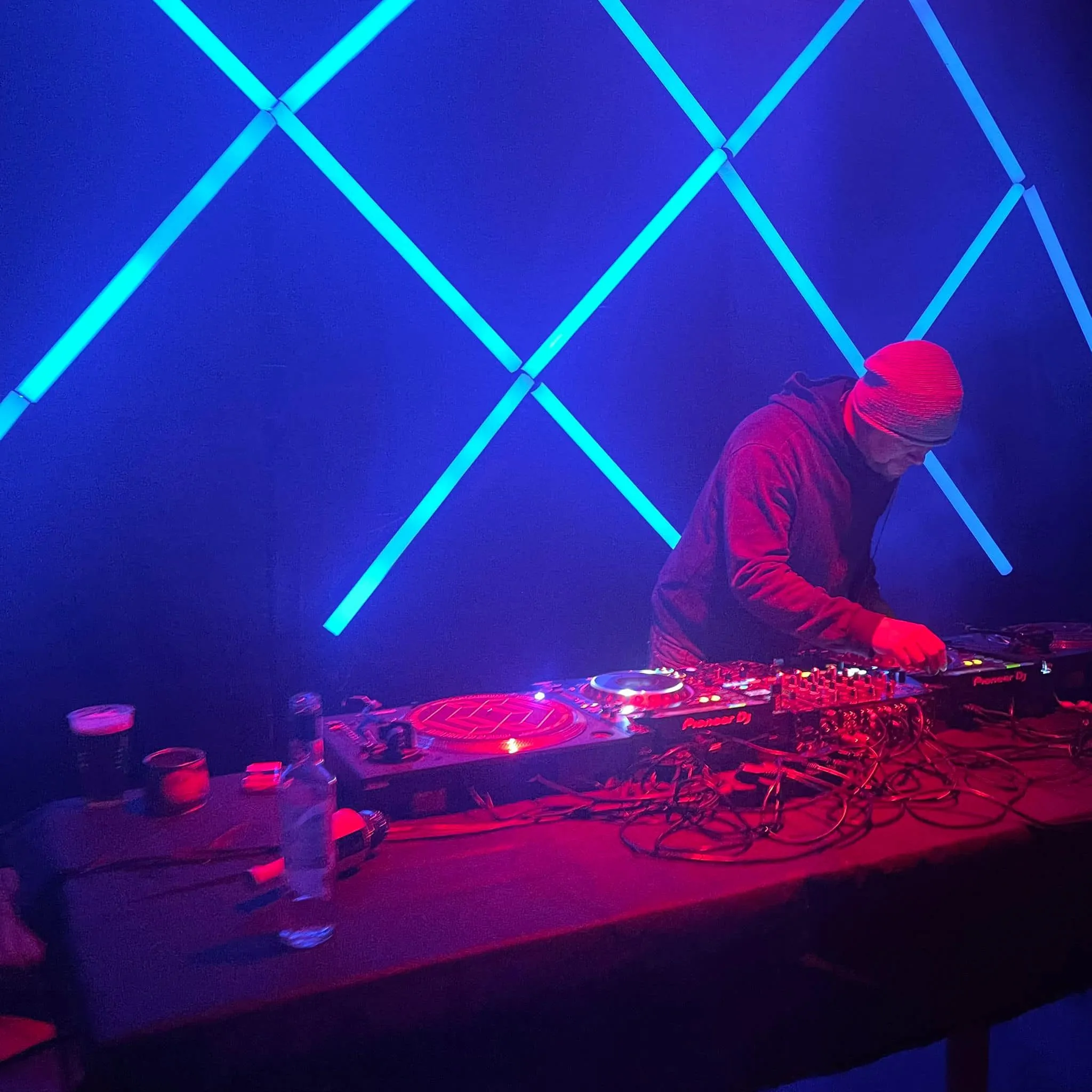 Ian Kita playing under blue neon light beams in a smoky club
